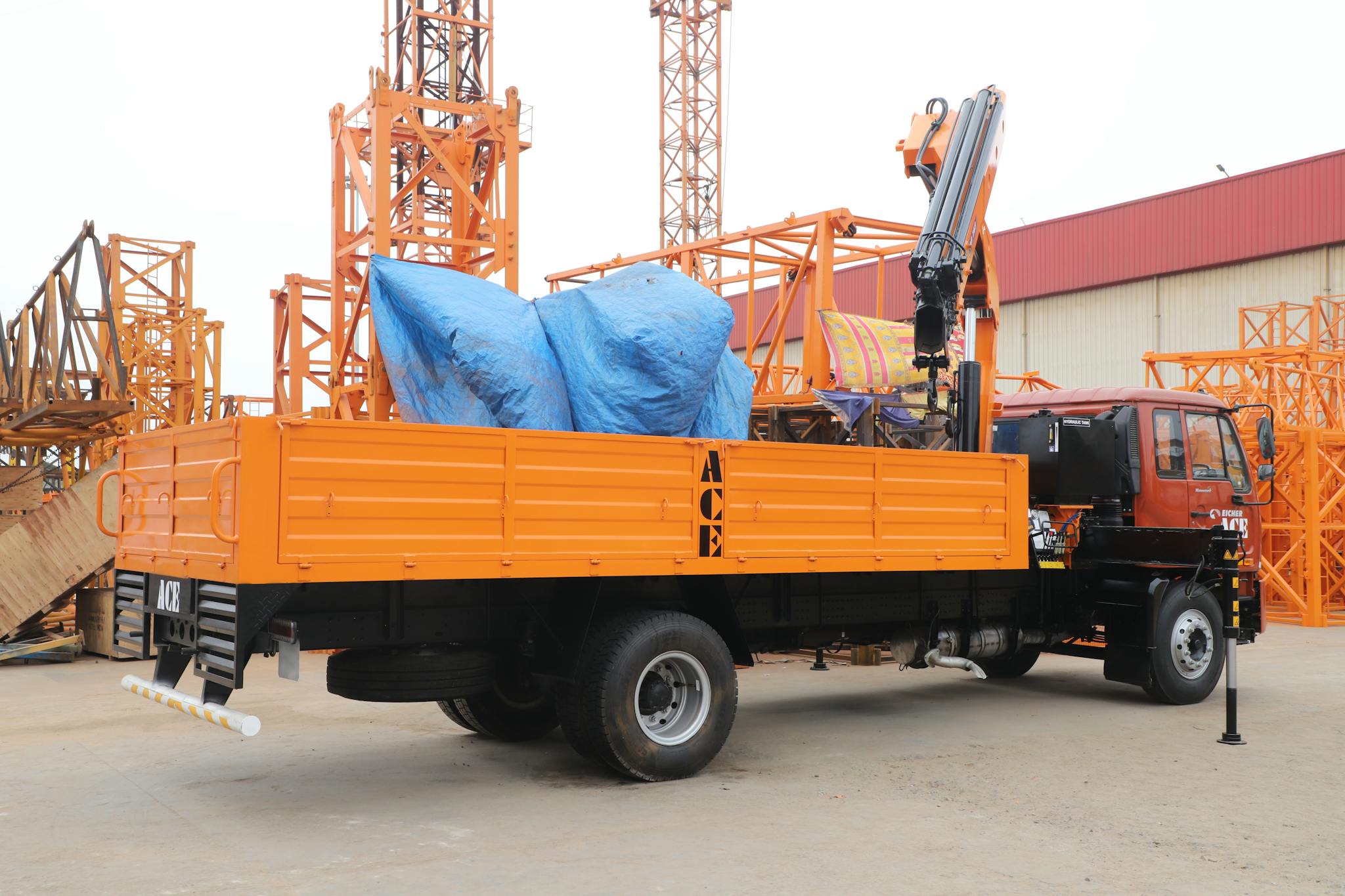 Home Orange truck with crane at construction site in Faridabad, India.